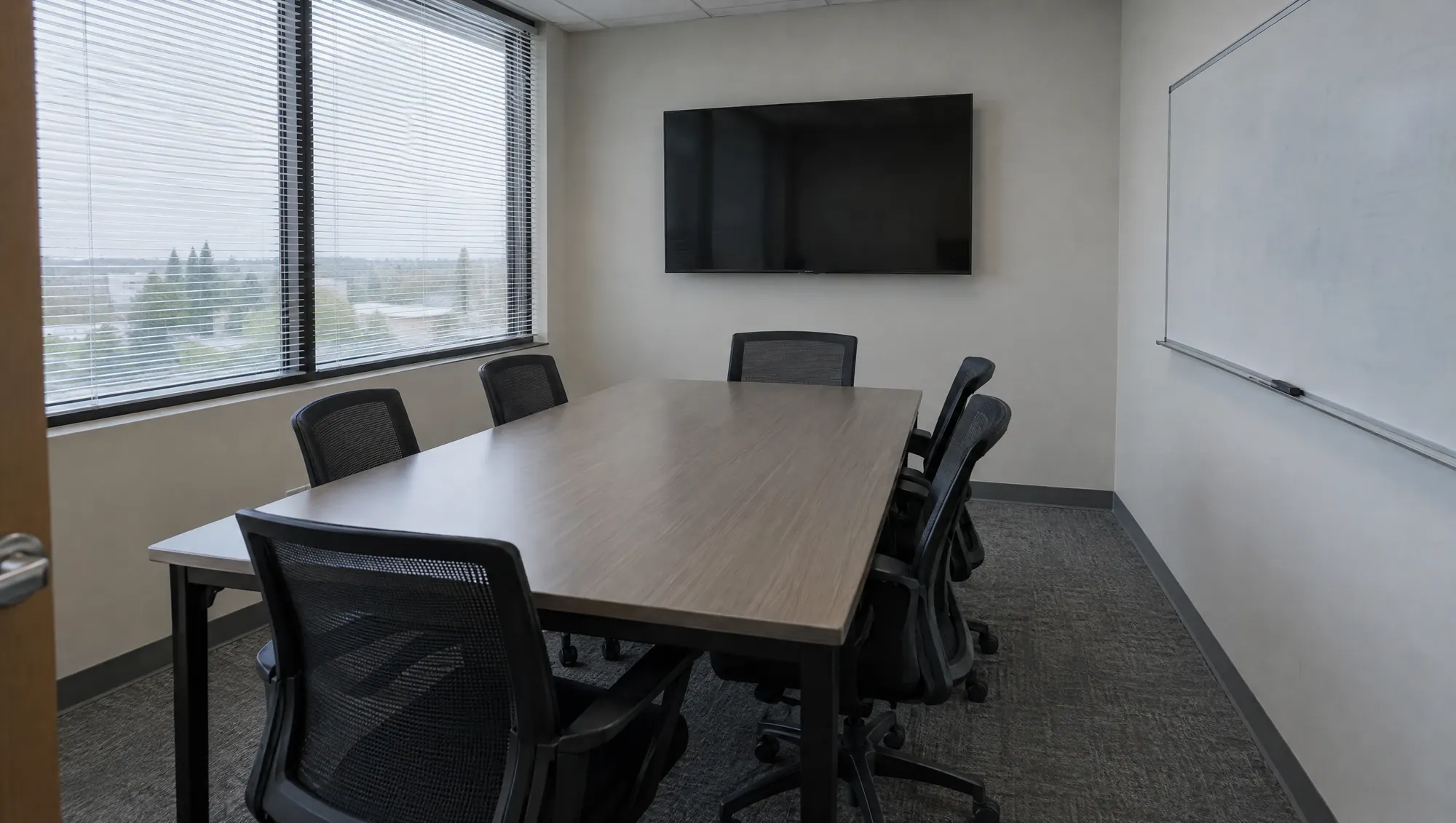 A small office conference room with the table wiped and chairs pushed in