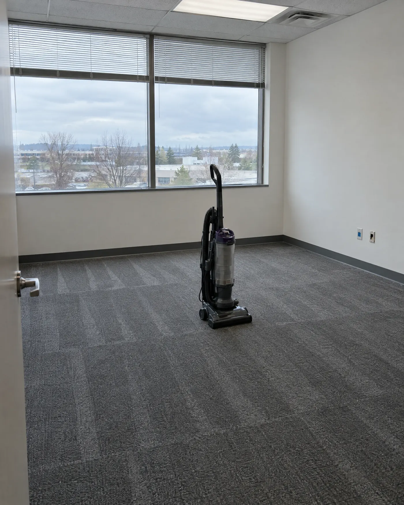 An empty office suite with freshly vacuumed carpet and an upright vacuum in the middle